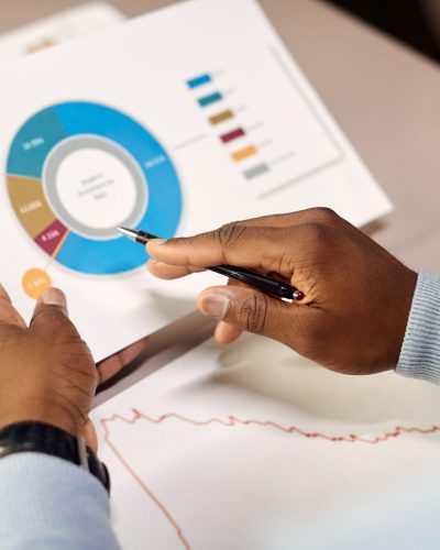 Close-up of black businessman examining diagrams and charts while going through paperwork and working in the office.